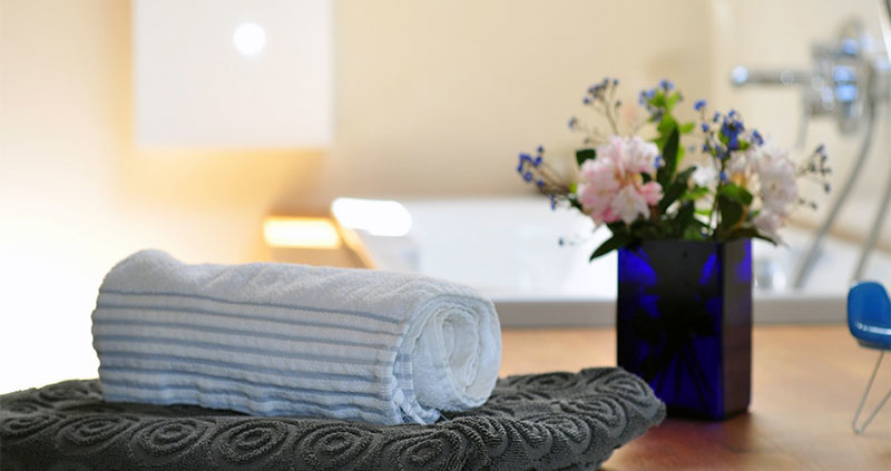 serviette et vase mis en avant avec fleurs dans une salle de bain